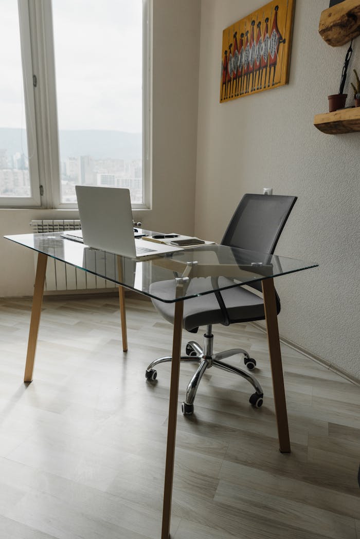 Sleek office setting with a glass desk and ergonomic chair overlooking a cityscape.